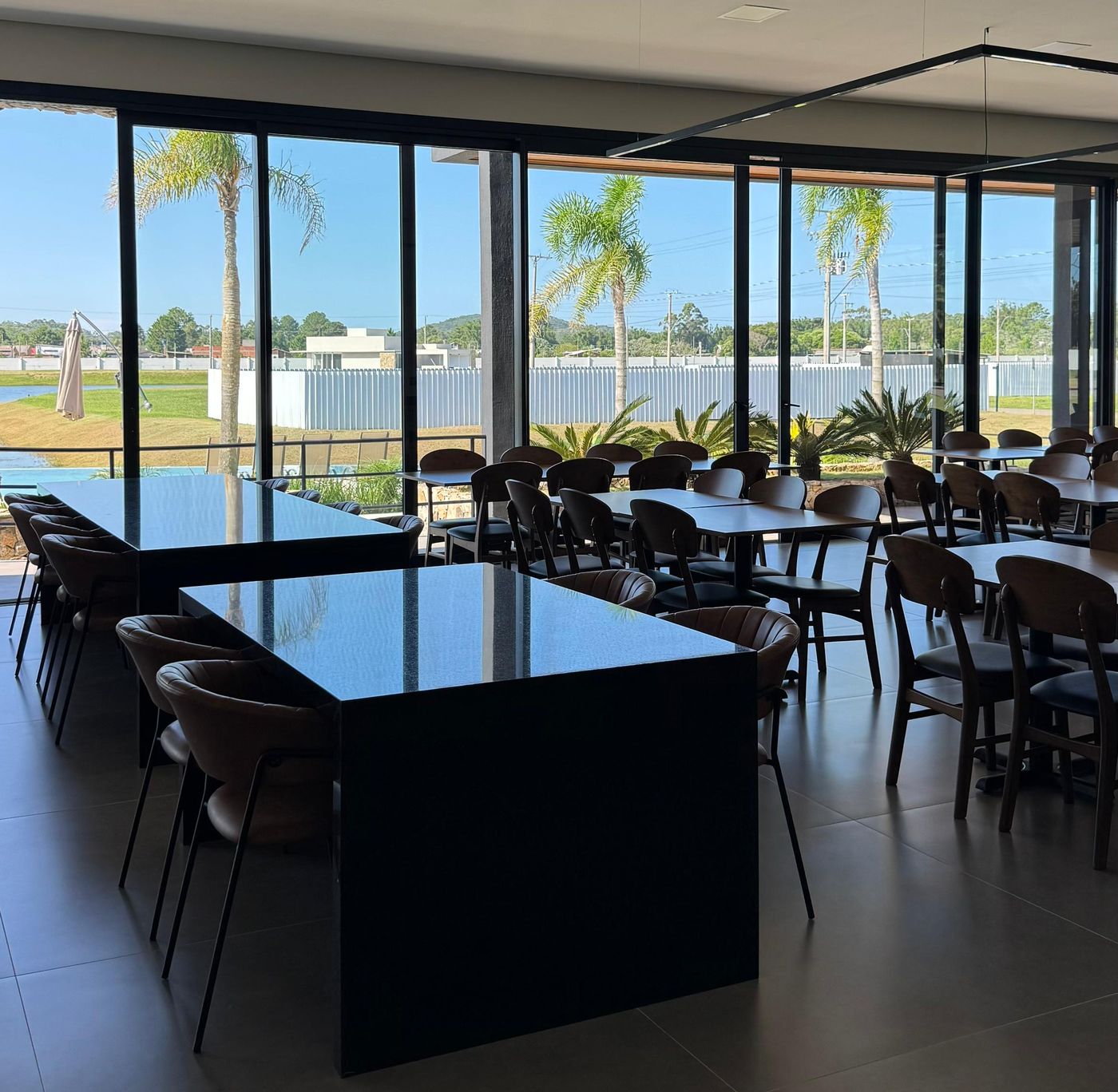 Salão do clube com mesas e vista para o lago