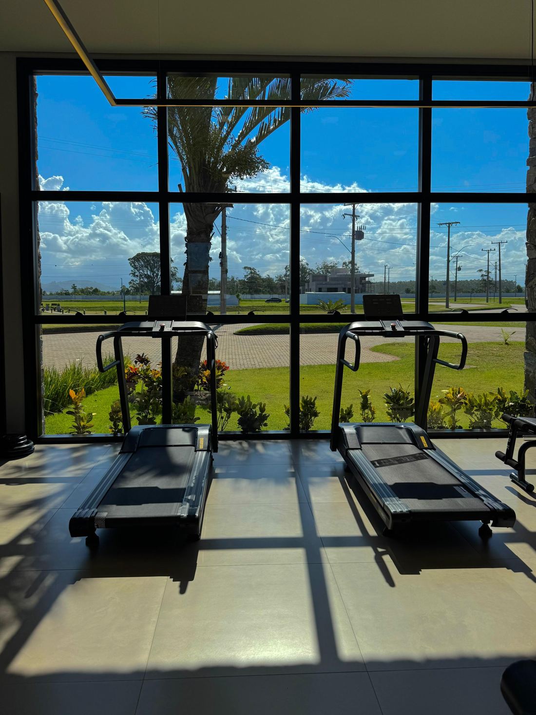 Academia com esteiras e vista para o jardim
