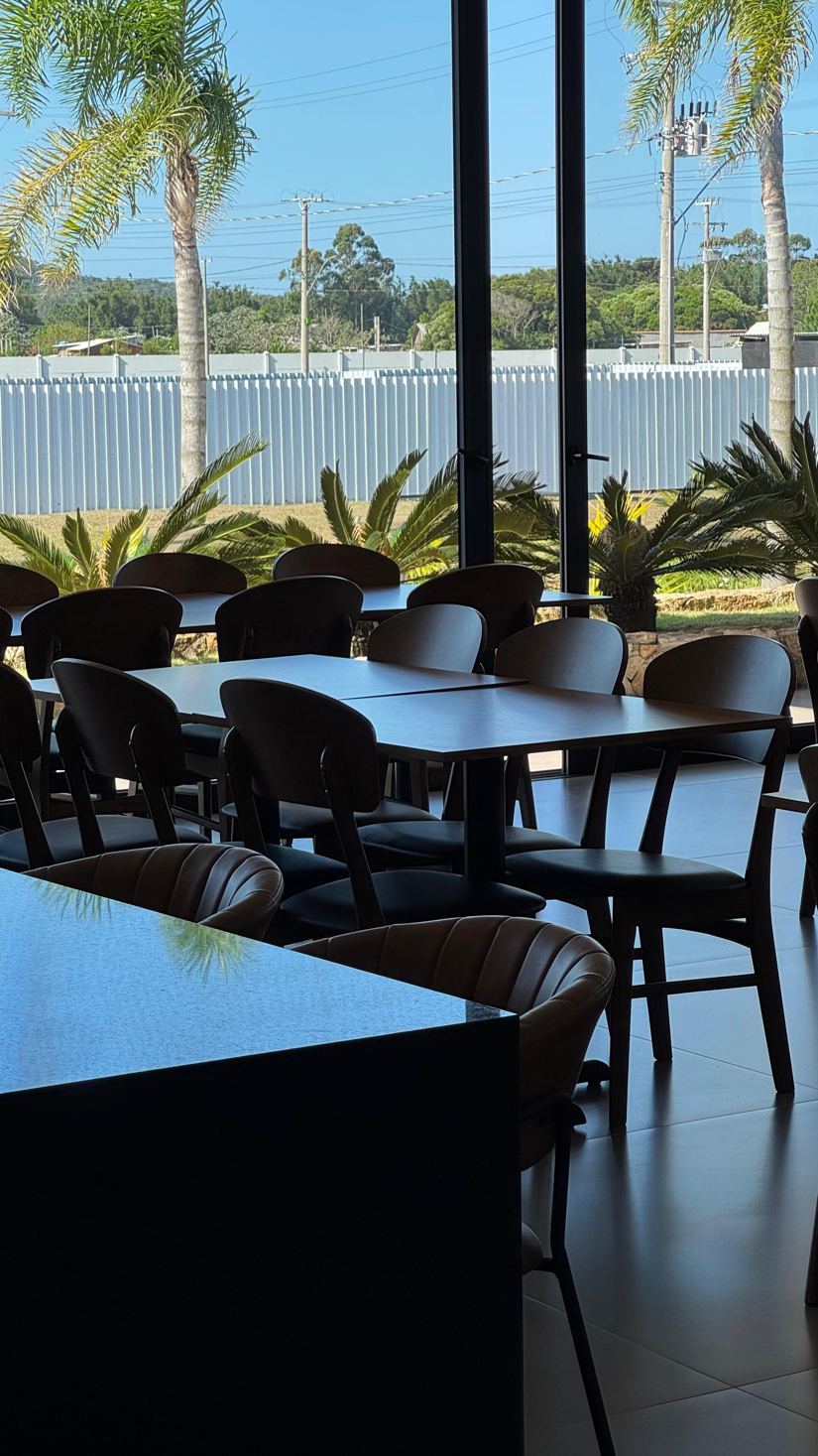 Espaço gourmet com mesas e jardim ao fundo